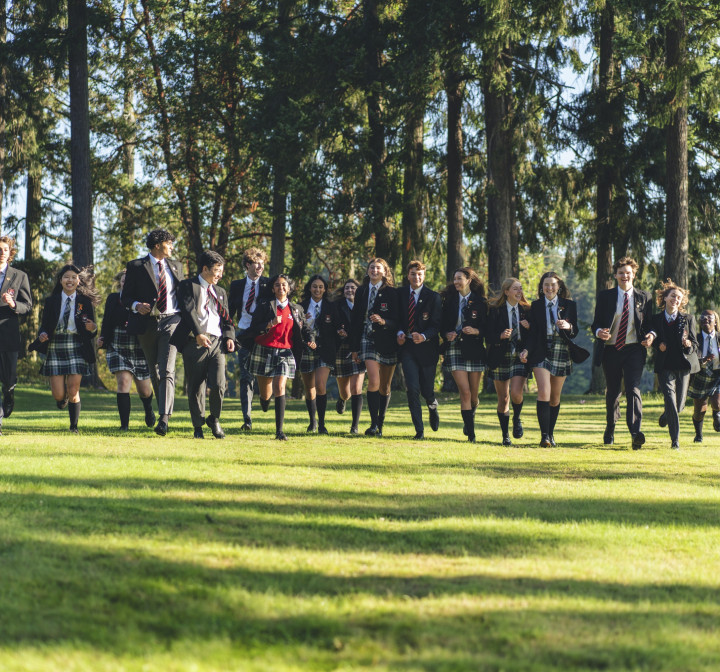 Schüler der Brentwood College School (Kanada) laufen in Uniform über den Rasen.