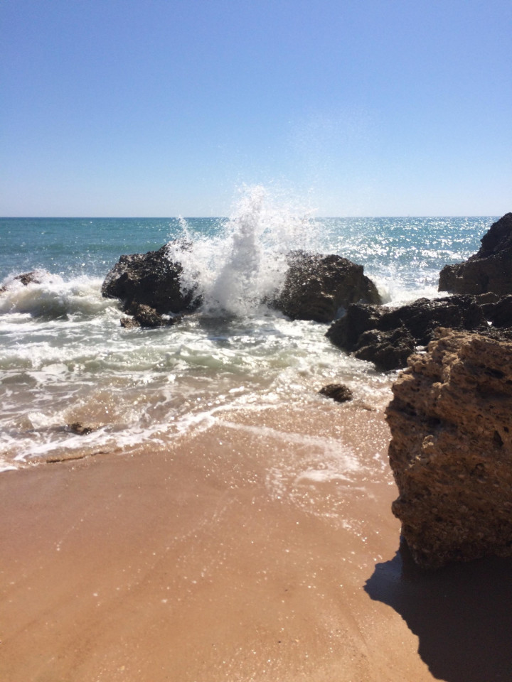 Strandfoto mit Felsen und Brandung.