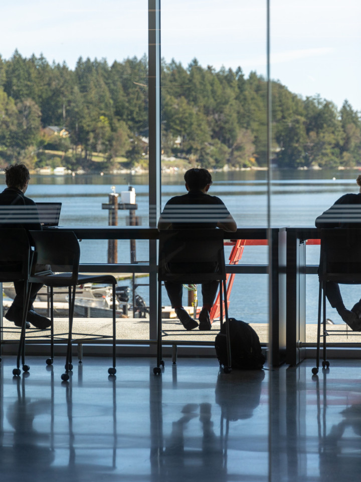 3 Schüler sitzen an der Glasfront im Lerncenter der Brentwood College School mit Blick auf die Bucht.