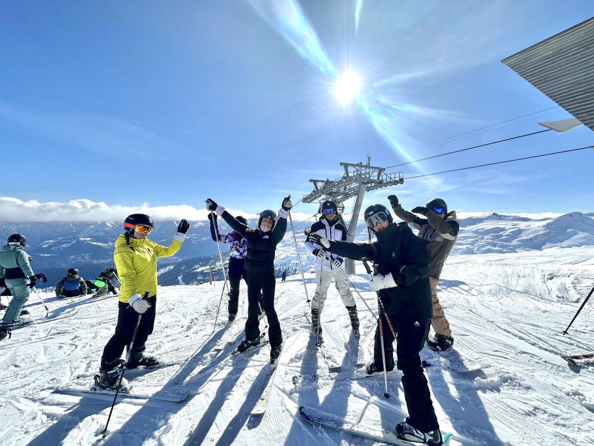 Spaß am Ski Day - Jungen und Mädchen stehen am Berg oben in der Sonne.