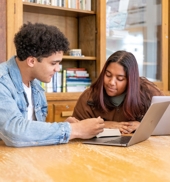 Junge und Mädchen im Klassenzimmer beim Arbeiten mit MAC Laptop