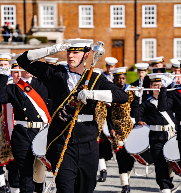 Schülerschaft in Kadettenuniform beim Marschieren auf dem Campus (Marching Band)