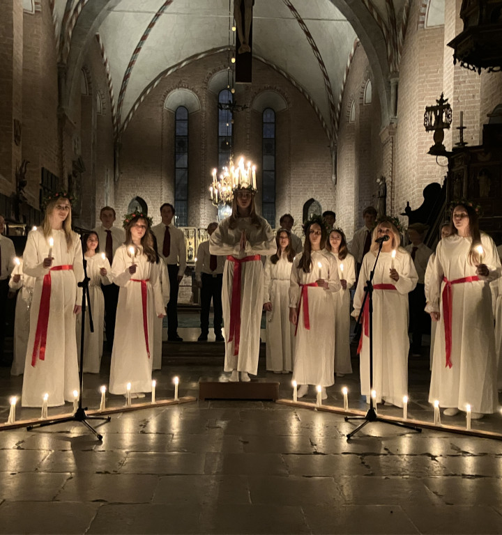 Feierlichkeiten zum Luziafest in der Kirche mit Mädchen in weißem Gewand und Luziakerze