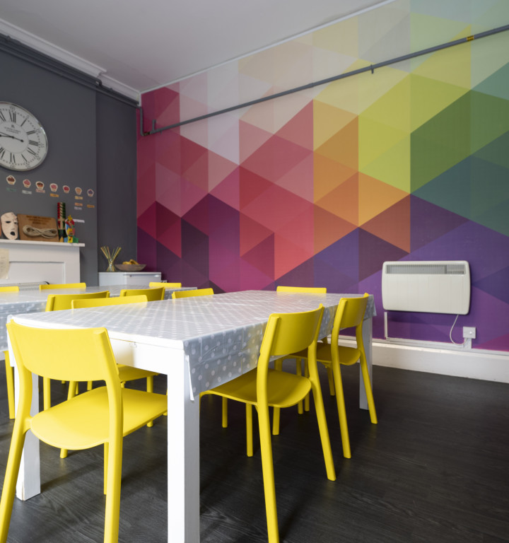 Küche im Boarding-Haus mit toller bunter Wand und fröhlich glben Stühlen
