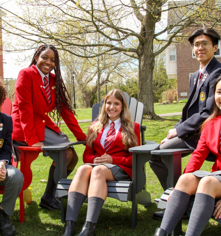Schülerinnen und Schüler sitzen in Schulunfirom auf Deckchairs im Freien